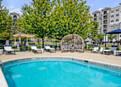 Thumbnail 35 of 53 - A swimming pool surrounded by trees and chairs.