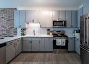 Thumbnail 27 of 47 - A modern kitchen with stainless steel appliances and wooden flooring.