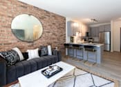 Thumbnail 24 of 47 - A modern living room with a brick wall and a round mirror.