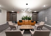 Thumbnail 45 of 47 - A modern waiting room with a wooden table and grey chairs.