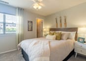 Thumbnail 4 of 23 - A bedroom with a large bed, a ceiling fan, and a window with blinds.