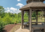 Thumbnail 13 of 23 - A gazebo with a wooden bench sits in a park.
