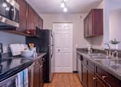 Thumbnail 20 of 23 - A kitchen with dark brown cabinets and a black counter top.