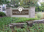 Thumbnail 8 of 23 - A sign for Windsor Estate Apartment Homes is in front of a building.