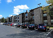 Thumbnail 5 of 23 - A parking lot with cars parked in front of a building.