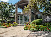 Thumbnail 1 of 23 - A leasing center is surrounded by flowers and trees.