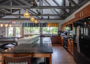 Thumbnail 32 of 44 - A kitchen with a black granite countertop and wooden cabinets.