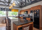 Thumbnail 30 of 44 - A kitchen with a black granite countertop and wooden cabinets.