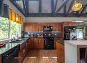 Thumbnail 31 of 44 - A kitchen with wooden cabinets and black appliances.