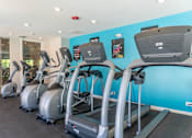 Thumbnail 26 of 44 - A gym with treadmills and elliptical machines.