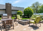 Thumbnail 23 of 44 - A patio with a table, chairs, and a fire pit.