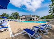 Thumbnail 17 of 44 - A poolside area with sun loungers and a building in the background.