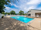 Thumbnail 15 of 44 - A large outdoor swimming pool with a diving board and a building in the background.