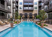 Thumbnail 16 of 19 - A large swimming pool in the middle of a courtyard surrounded by potted plants and chairs.
