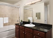 Thumbnail 5 of 18 - A bathroom with a black countertop and a white sink.
