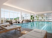 Thumbnail 3 of 14 - A large indoor swimming pool with lounge chairs and a view of the outdoors.