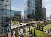 Thumbnail 4 of 14 - A modern glass building with a green lawn in front.
