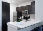 Thumbnail 12 of 13 - a kitchen with white countertops and black cabinets at AVE Las Colinas, Irving, 75038