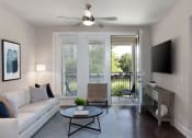 Thumbnail 2 of 13 - a living room with a ceiling fan and a sliding glass door to a balcony at AVE Las Colinas, Irving