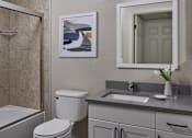 Thumbnail 4 of 18 - A bathroom with a toilet, sink, and a framed picture on the wall.