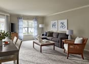 Thumbnail 2 of 18 - A living room with a grey couch, a wooden table and a television.