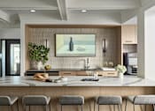 Thumbnail 17 of 18 - A modern kitchen with a large island and grey bar stools.