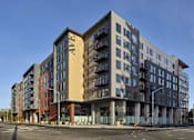 Thumbnail 9 of 30 - A large, modern apartment building with multiple balconies and a variety of window designs.