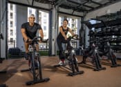 Thumbnail 4 of 20 - two men working out on exercise bikes in a gym at AVE Phoenix Terra, Phoenix, Arizona