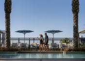 Thumbnail 1 of 20 - a man and woman standing next to a pool at a hotel with umbrellas at AVE Phoenix Terra, Arizona, 85003