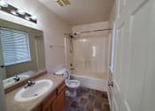 Thumbnail 34 of 41 - A bathroom with a sink, mirror, toilet, and bathtub.