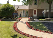 Thumbnail 3 of 39 - a sidewalk in front of a building with flowers and plants