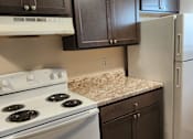 Thumbnail 7 of 18 - A kitchen with a white stove and a white refrigerator.