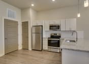 Thumbnail 5 of 18 - Kitchen with stainless steel appliances and white cabinets at The Augustan, Augusta, Georgia