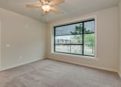 Thumbnail 2 of 18 - an empty living room with a large window and a ceiling fan at The Augustan, Augusta