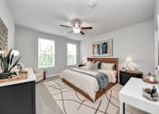 Thumbnail 12 of 18 - A bedroom with a large bed and a ceiling fan.