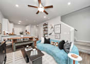 Thumbnail 12 of 19 - A living room with a blue couch and a ceiling fan.