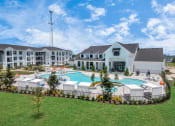 Thumbnail 36 of 37 - Resort style pool area with lounge chairs and the clubhouse and apartments in the background