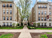 Thumbnail 3 of 23 - A row of brown and beige apartment buildings with green lawns in front.