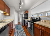 Thumbnail 25 of 53 - A kitchen with a black refrigerator and stove top oven.