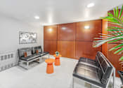 Thumbnail 27 of 28 - building lobby with black leather couches and orange stools