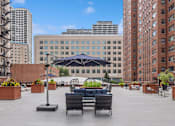 Thumbnail 7 of 45 - a seating area with couches and chairs on a roof top with a view of the city