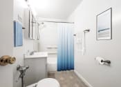 Thumbnail 12 of 33 - a bathroom with a white toilet and a blue shower curtain