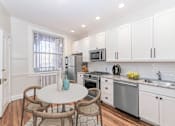 Thumbnail 8 of 38 - a kitchen with white cabinets and stainless steel appliances and a small table with four chairs