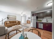 Thumbnail 7 of 37 - a living room with a white table and chairs and a kitchen with a stainless steel refrigerator and