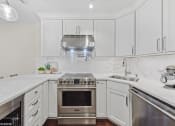 Thumbnail 17 of 62 - a white kitchen with stainless steel appliances and white cabinets