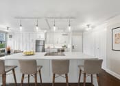 Thumbnail 6 of 62 - a kitchen with white cabinets and a white counter top and chairs