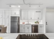 Thumbnail 7 of 62 - a kitchen with white cabinets and a stainless steel refrigerator