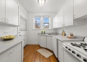 Thumbnail 7 of 24 - a kitchen with white cabinets and a stove and a window