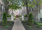 Thumbnail 2 of 24 - a walkway with trees and shrubs in front of an apartment building