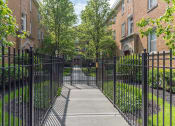 Thumbnail 22 of 22 - a gated entrance to a brick building with trees in the background